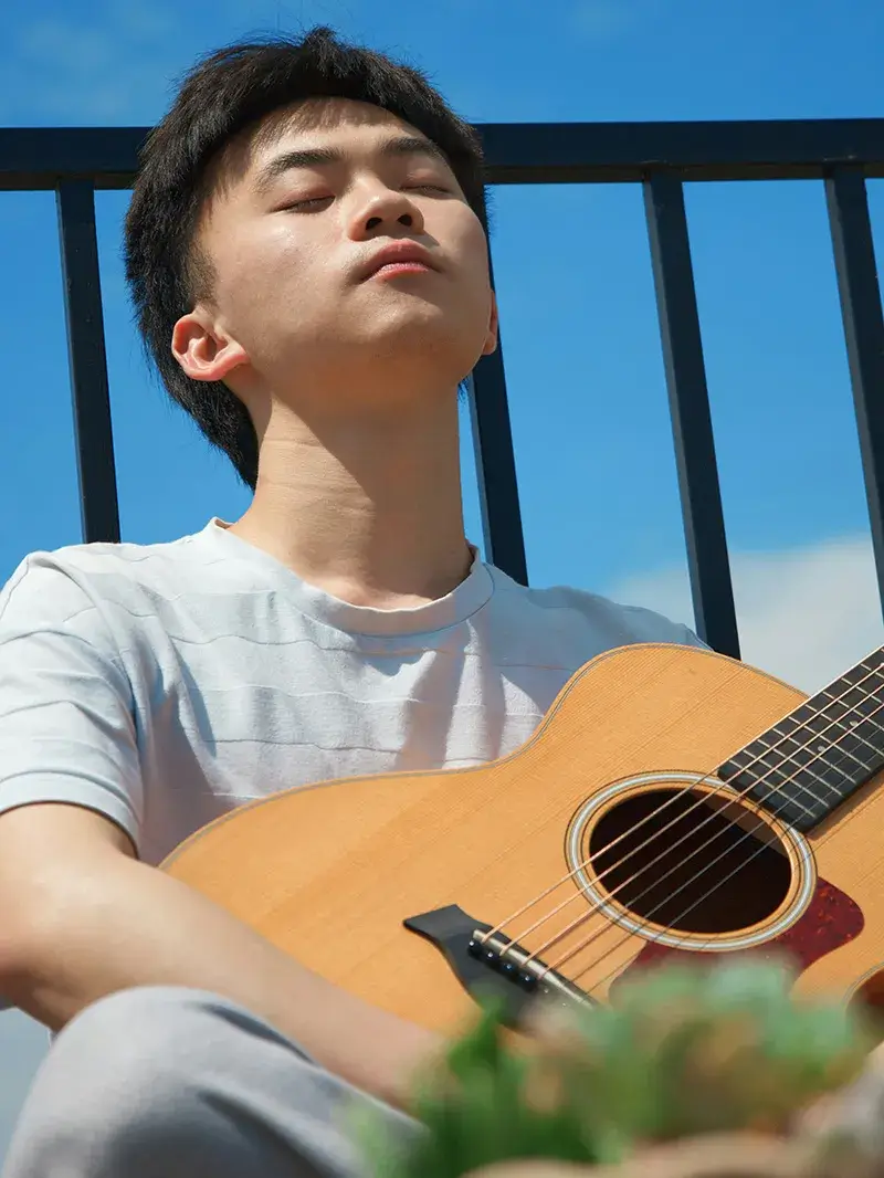 Here to Listen Youth sitting outside playing guitar