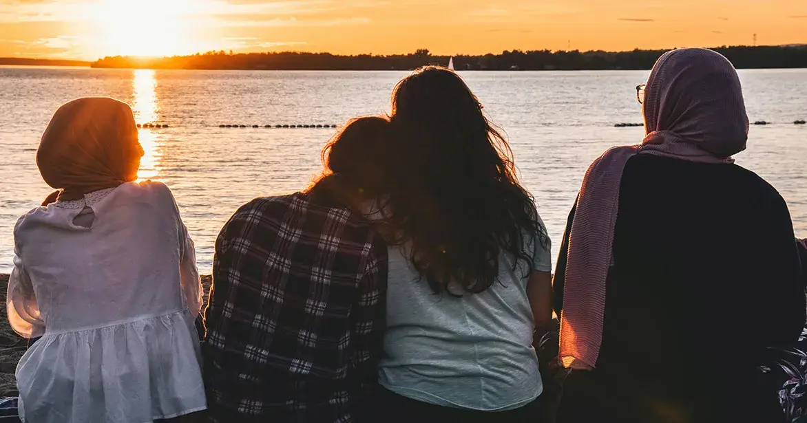 Trusted Adult CTA Group sitting next to lake at sunset