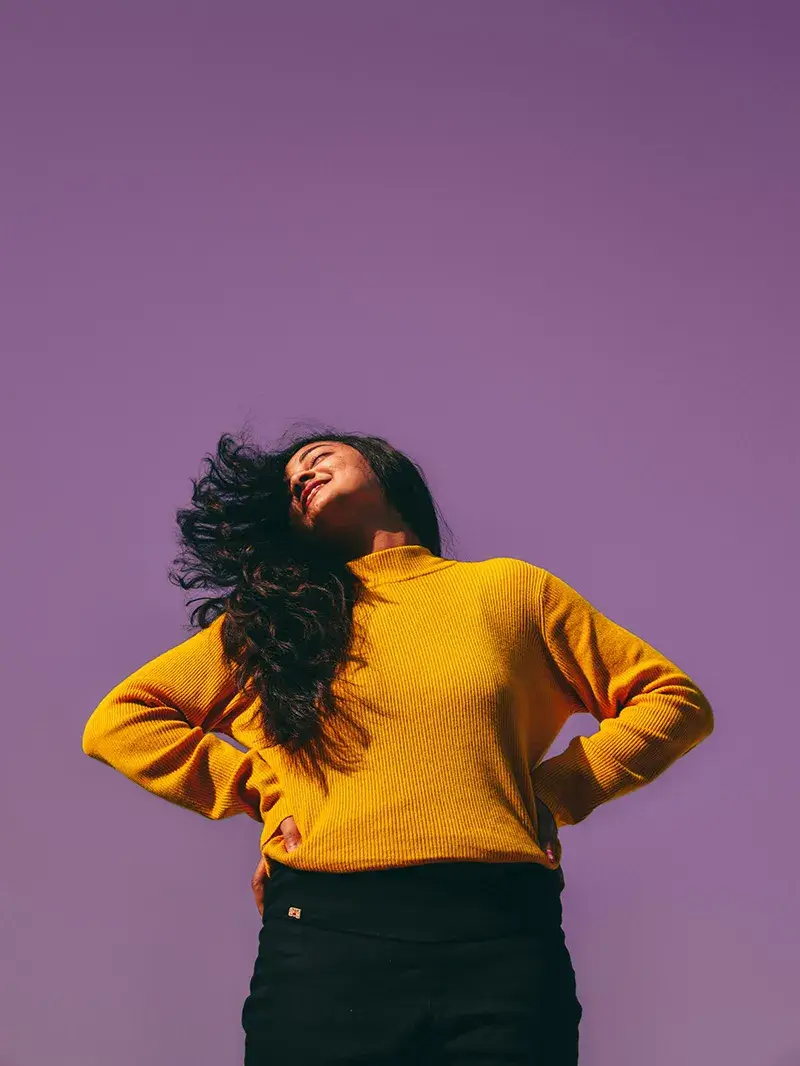 What We've Done Girl in yellow sweater in front of purple background