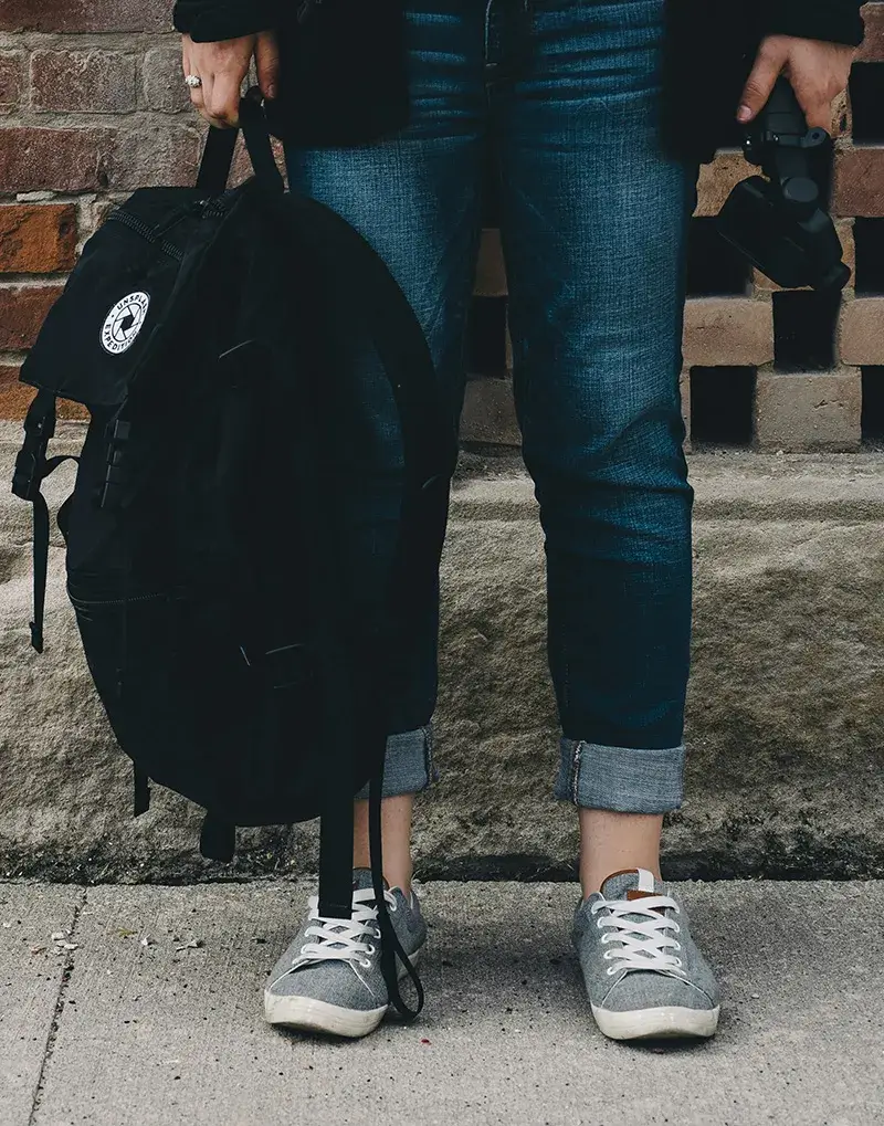 teen-holding-backpack A teenager holding a black backpack