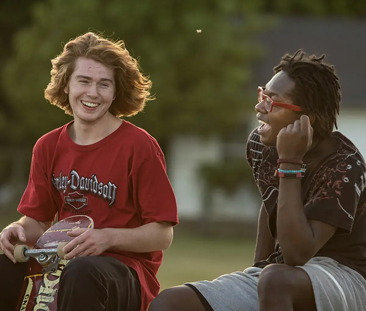 SHAPE Two teenagers laughing while at a skate park