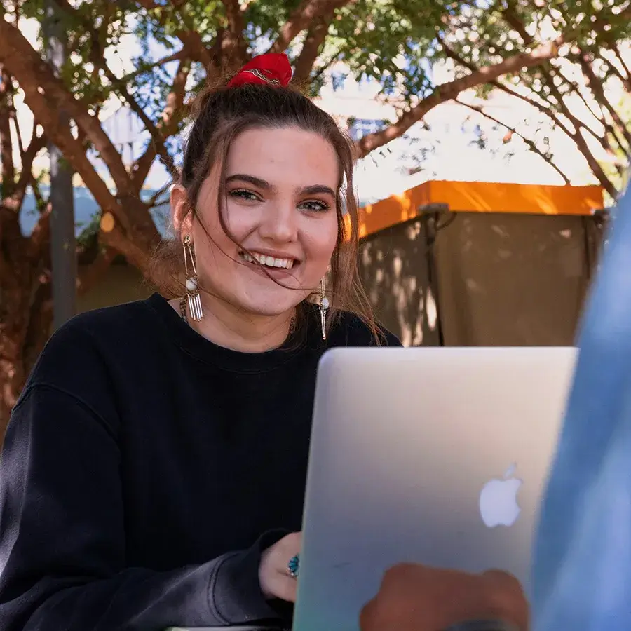 questions A teen girl smiles as she researches on her laptop