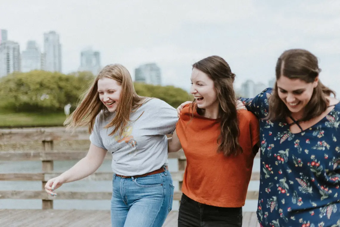 Three teenage girls walk with their arms around one another
