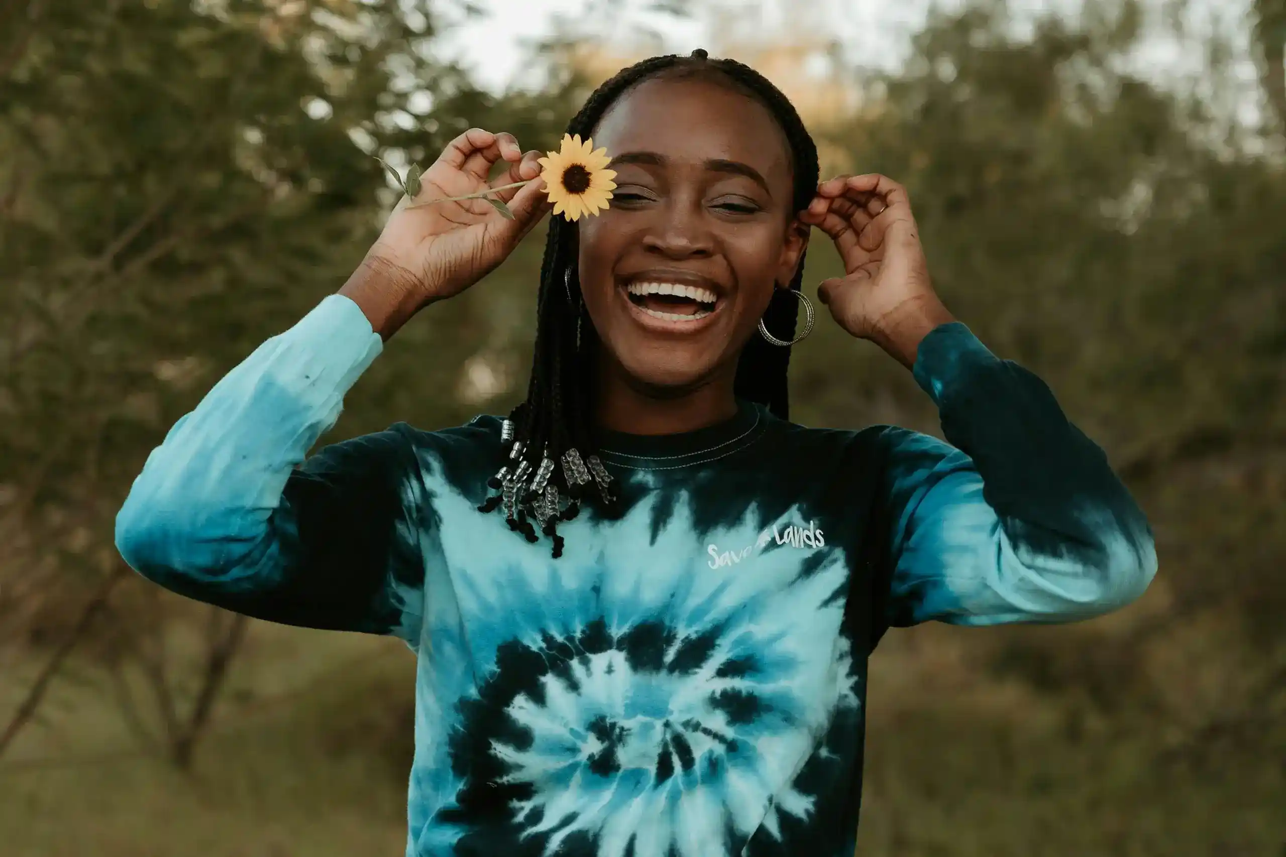 A young teen smiling with a flower behind their ear