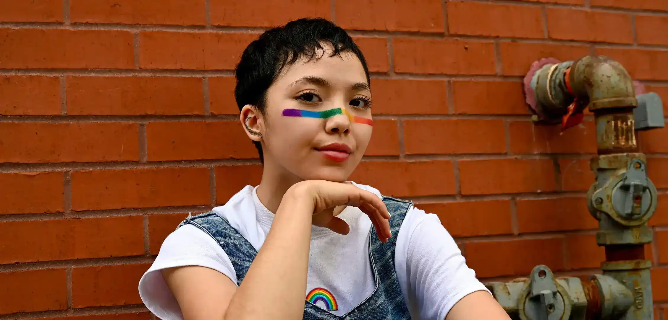 A young person with rainbow makeup on their face